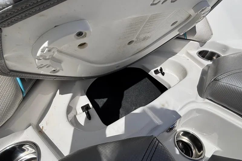 Slide: The Image of 2017 MasterCraft XT23 boat interior storage compartment with open seat and cup holders. - 50