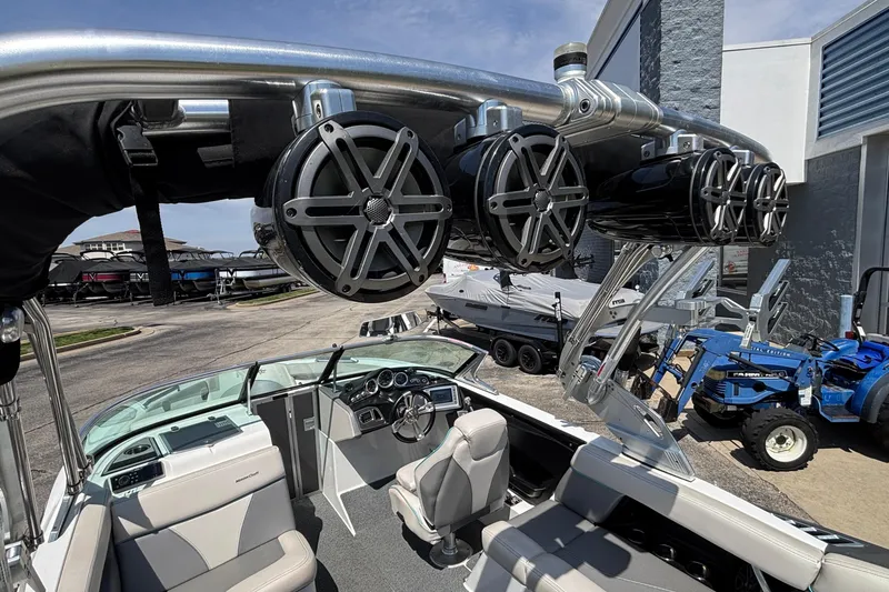 Slide: The Image of 2017 MasterCraft XT23 boat interior with speakers and seating, parked near other boats and equipment. - 56