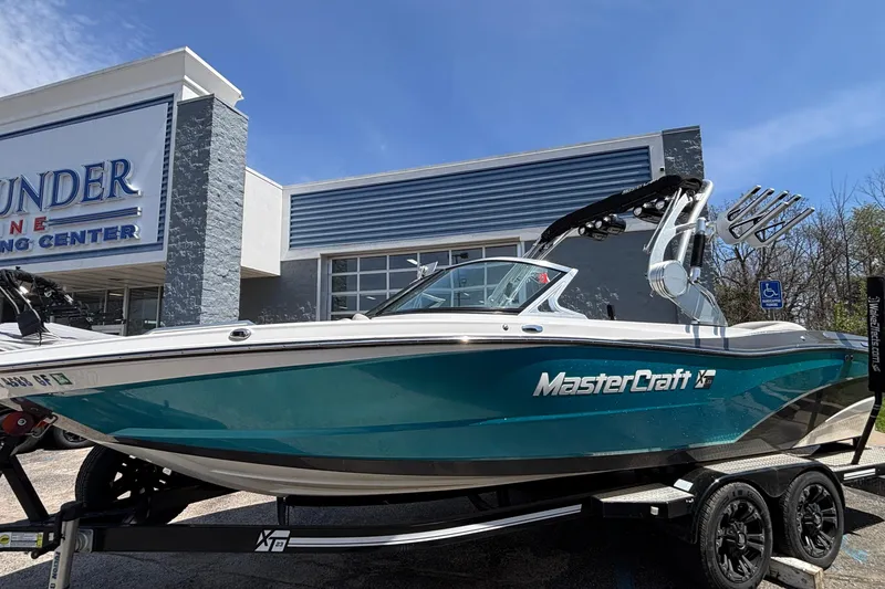 Slide: The Image of 2017 MasterCraft XT23 boat on trailer outside dealership under clear blue sky. - 60