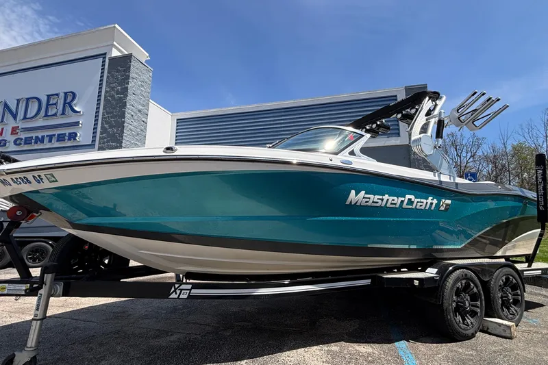 Slide: The Image of 2017 MasterCraft XT23 boat on trailer outside dealership, blue and white design. - 61