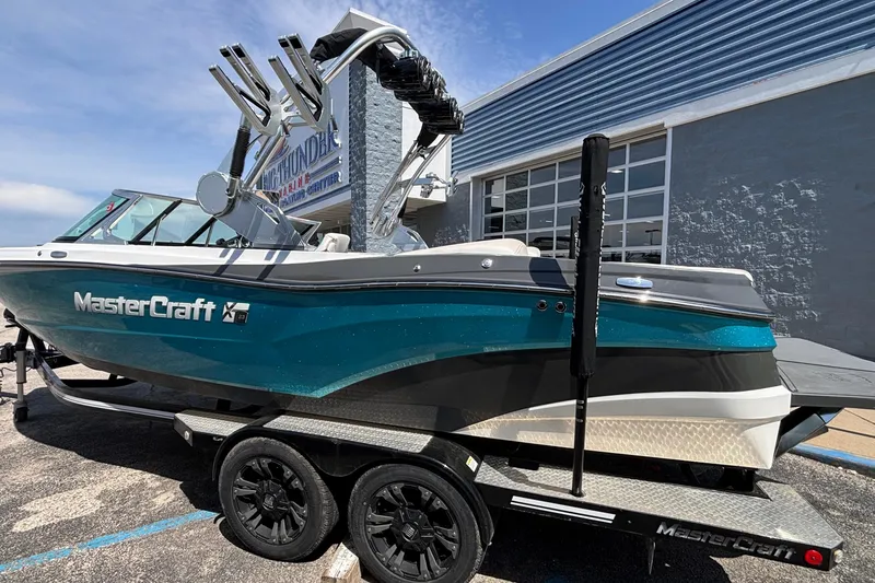 Slide: The Image of 2017 MasterCraft XT23 boat on trailer, teal and white design, parked outside dealership. - 62