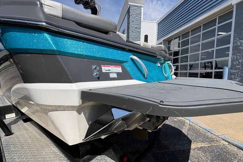 Slide: The Image of 2017 MasterCraft XT23 boat with teal and black exterior near a modern building. - 63