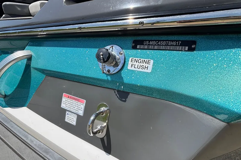 Slide: The Image of 2017 MasterCraft XT23 boat with engine flush port and warning labels. - 66