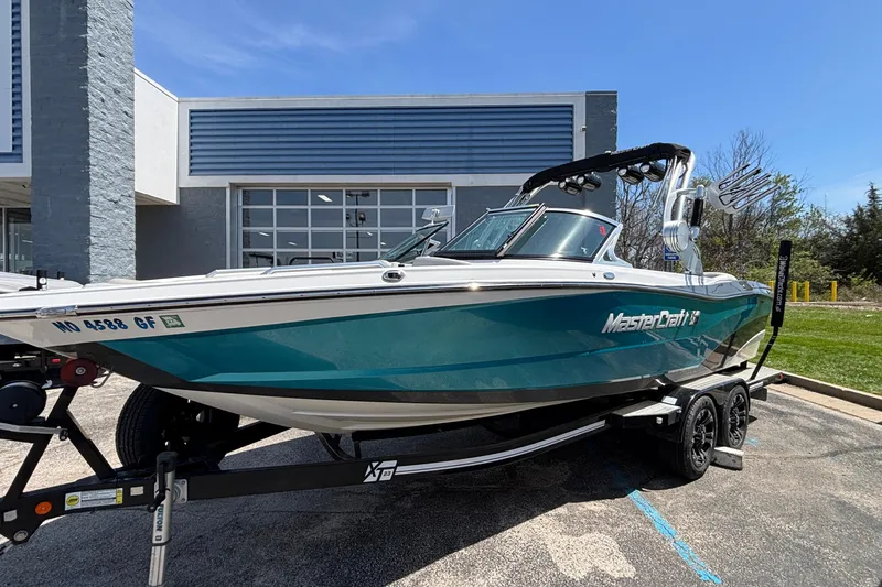 Slide: The Image of 2017 MasterCraft XT23 boat on trailer, parked outside a modern building. - 67