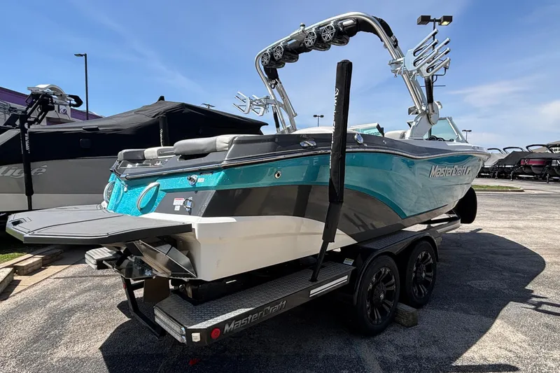 Slide: The Image of 2017 MasterCraft XT23 boat on trailer, turquoise and gray design, parked outdoors. - 72