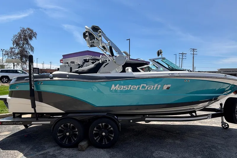 Slide: The Image of 2017 MasterCraft XT23 boat on trailer, turquoise and gray design, parked outdoors. - 73