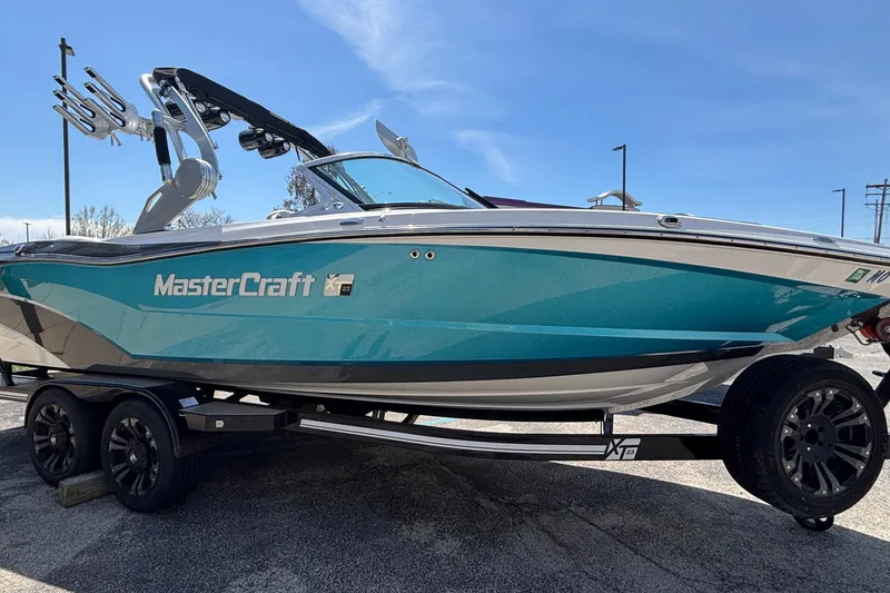 Slide: The Image of 2017 MasterCraft XT23 boat on trailer, turquoise and white, under clear blue sky. - 74