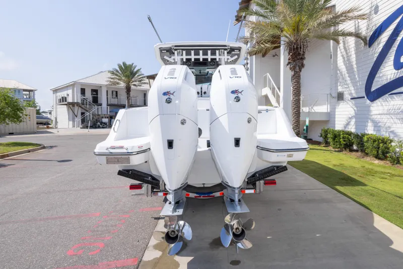Slide: The Image of 2026 Crevalle 33 CSF boat with dual outboard engines, parked near a coastal building. - 18