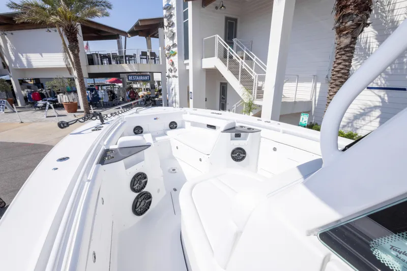 Slide: The Image of 2026 Crevalle 33 CSF boat interior with seating and speakers, docked near a restaurant. - 49