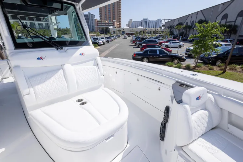 Slide: The Image of 2026 Crevalle 33 CSF boat interior with white seating, parked cars, and buildings in the background. - 51