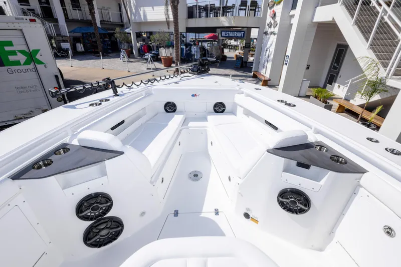 Slide: The Image of 2026 Crevalle 33 CSF boat interior with seating and speakers, docked near a restaurant. - 58