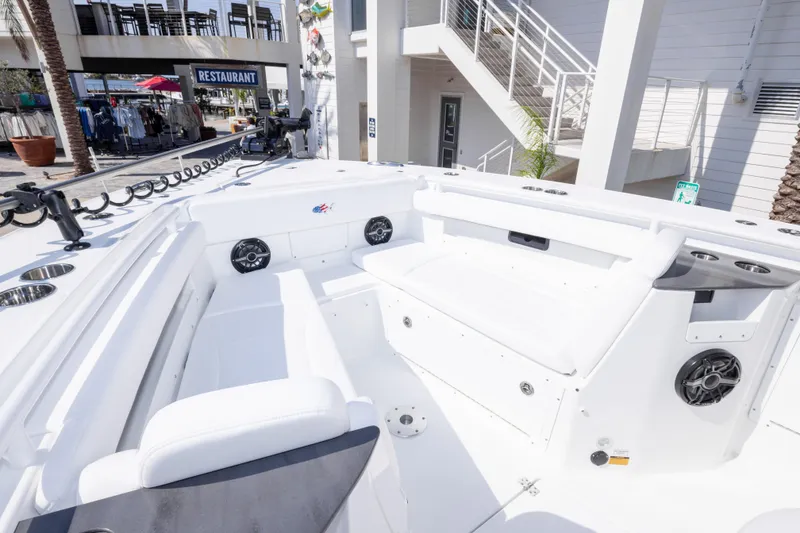 Slide: The Image of 2026 Crevalle 33 CSF boat interior with white seating and speakers, docked near a restaurant. - 60