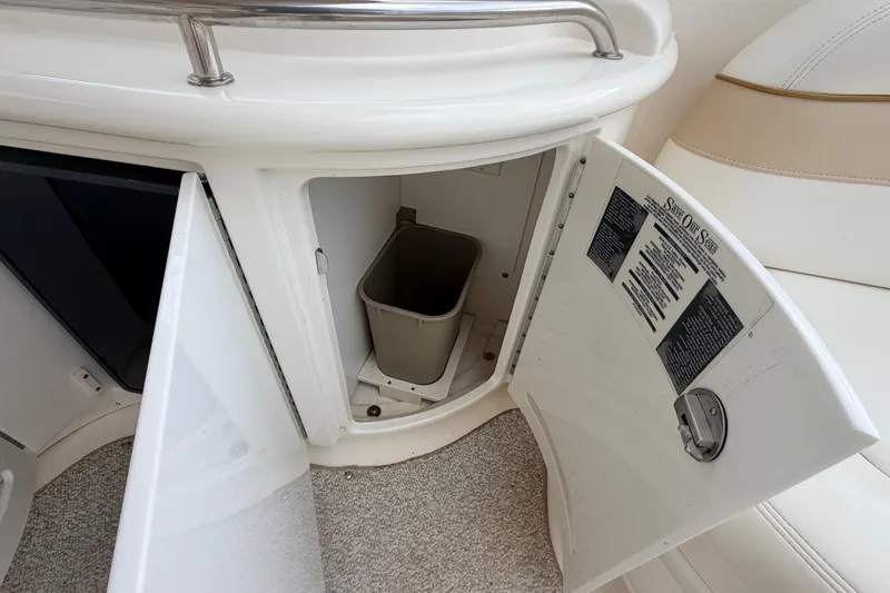 Slide: The Image of Open storage compartment on 2002 Sea Ray 290 Bowrider boat with trash bin inside. - 18