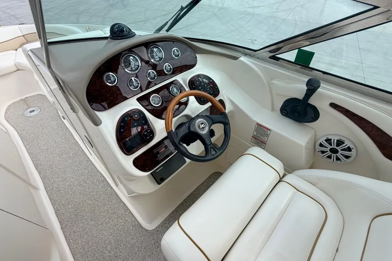 Slide: The Image of 2002 Sea Ray 290 Bowrider cockpit with wood-accented dashboard and steering wheel. - 21