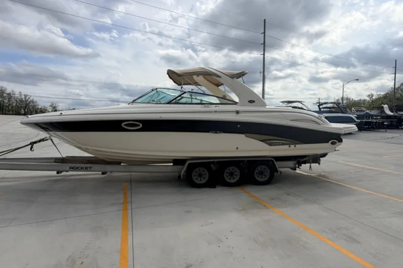 Slide: The Image of 2002 Sea Ray 290 Bowrider on trailer under cloudy sky in parking lot. - 4