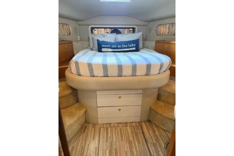 Slide: The Image of 1997 Sea Ray 420 Aft Cabin bedroom with striped bedding and "meet me at the lake" pillow. - 19