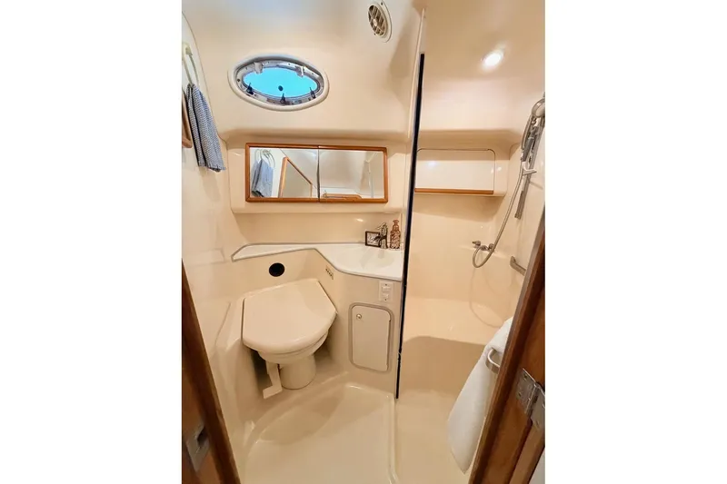 Slide: The Image of 1997 Sea Ray 420 Aft Cabin bathroom with shower, sink, and porthole window. - 20