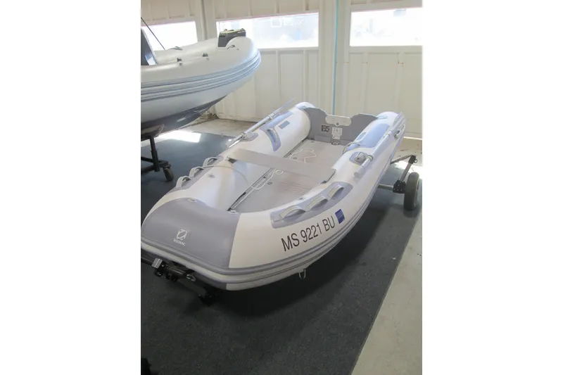 Slide: The Image of 2023 Zodiac Cadet 310 Alu inflatable boat displayed indoors on a trailer. - 7