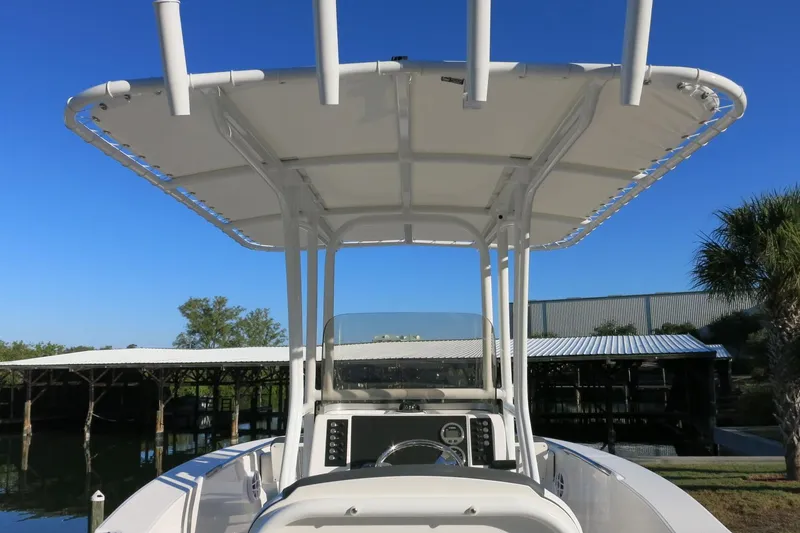 Slide: The Image of 2026 Robalo R202 Explorer boat with T-top and console, docked under clear blue sky. - 20