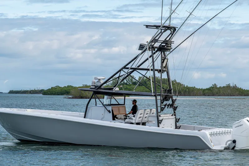 Slide: The Image of 2024 Contender 44 ST boat cruising on a calm waterway with lush greenery in the background. - 29