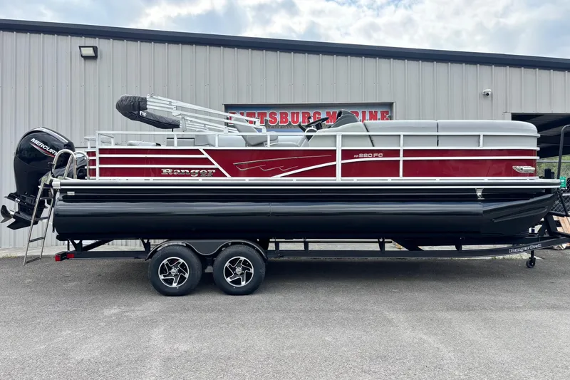 The Image of 2025 Ranger Reata 220FC pontoon boat on trailer, parked outside a marine building. - 1
