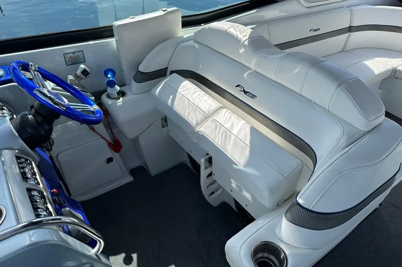 Slide: The Image of Interior of a 2012 Formula 350 FX6 boat with white seating and blue steering wheel. - 14