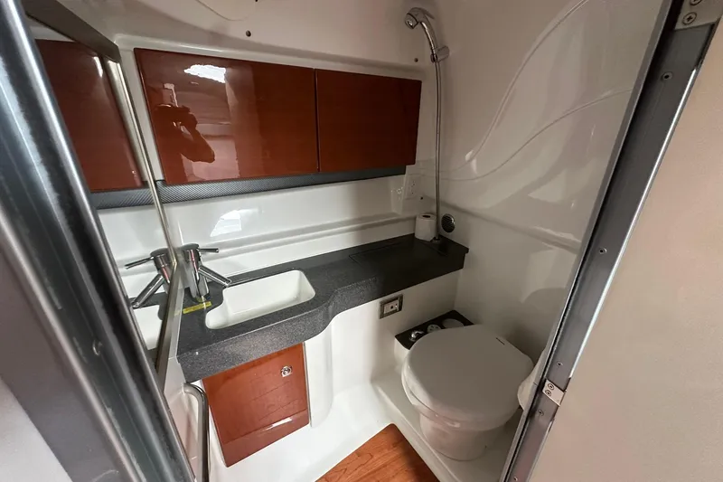 Slide: The Image of Compact bathroom in a 2012 Formula 350 FX6 boat, featuring sink, toilet, and storage cabinets. - 21