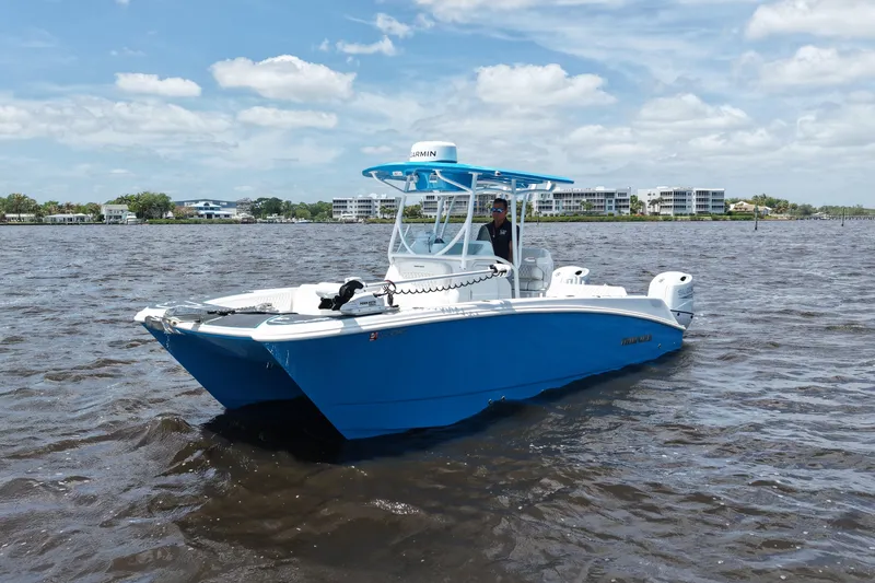 Slide: The Image of 2024 Twin Vee 240 GFX CC boat on water, blue hull, clear sky background. - 2