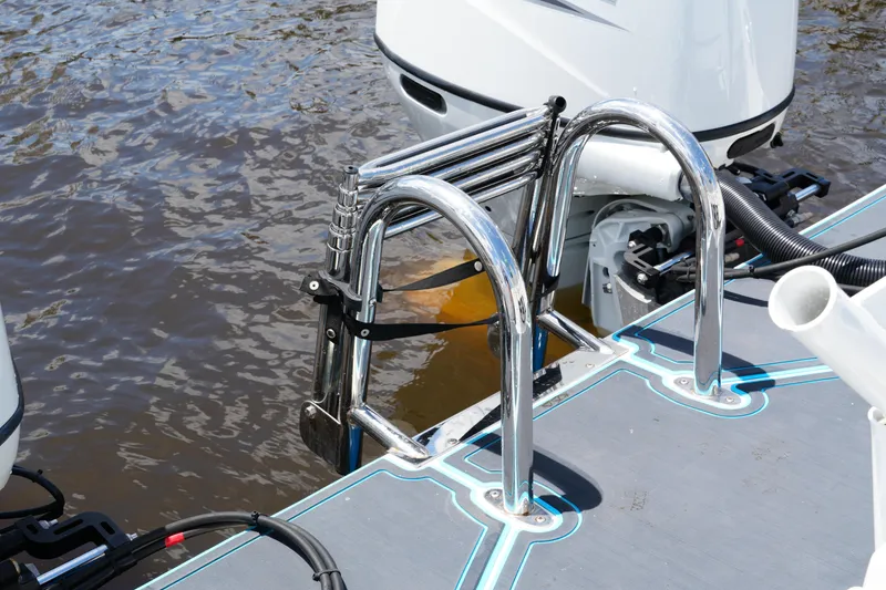 Slide: The Image of 2024 Twin Vee 240 GFX CC boat ladder and motor detail on water. - 26