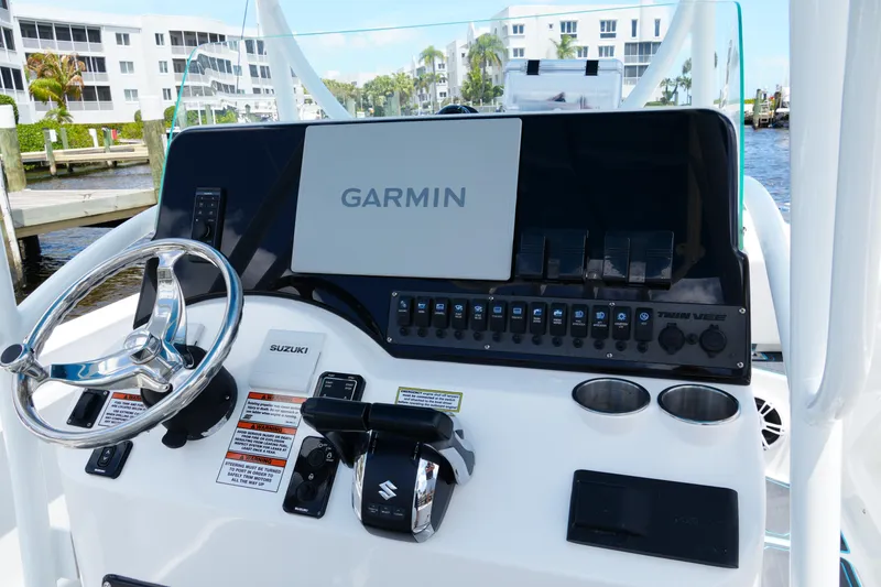 Slide: The Image of 2024 Twin Vee 240 GFX CC boat dashboard with Garmin navigation system and Suzuki controls. - 44