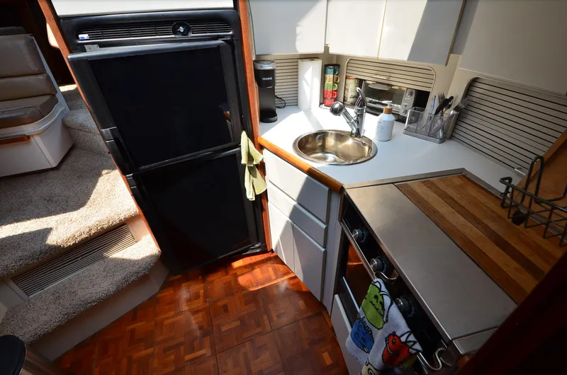Slide: The Image of 1991 Carver 33 Aft Cabin kitchen with fridge, sink, and wooden countertop. - 16