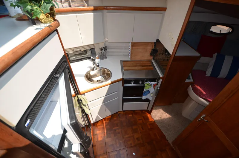 Slide: The Image of 1991 Carver 33 Aft Cabin kitchen with wood flooring and compact appliances. - 17