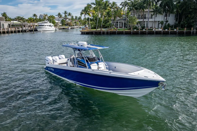 Slide: The Image of 2015 Nor-Tech 340 Sport Center Console boat on calm water, surrounded by palm trees. - 10