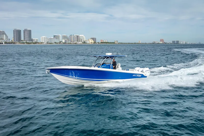 Slide: The Image of 2015 Nor-Tech 340 Sport Center Console boat cruising on open water near city skyline. - 29