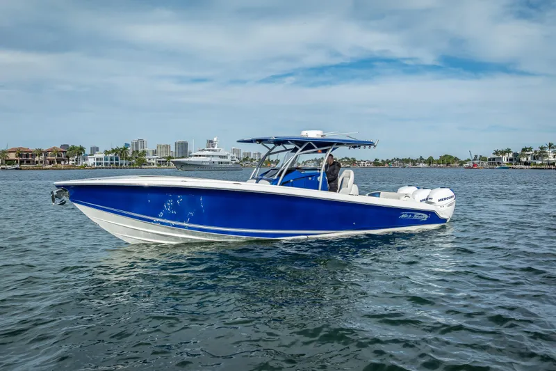 Slide: The Image of 2015 Nor-Tech 340 Sport Center Console boat on water, blue hull, cityscape background. - 3