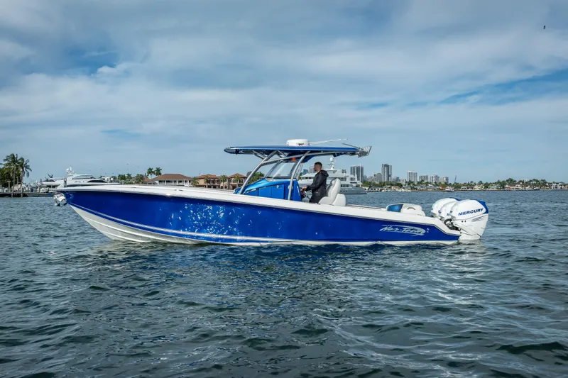 Slide: The Image of 2015 Nor-Tech 340 Sport Center Console boat cruising on water, blue hull, city skyline background. - 4