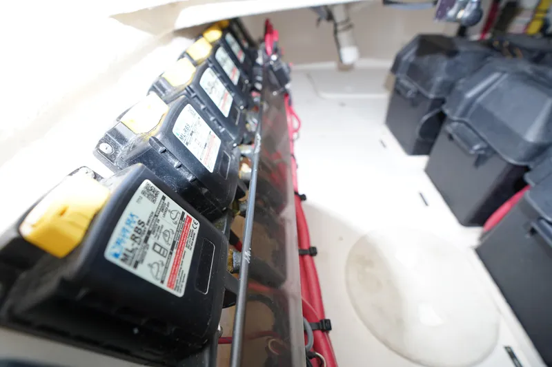 Slide: The Image of Battery compartment of a 2015 Intrepid 400 Cuddy boat, showcasing multiple batteries and wiring. - 102