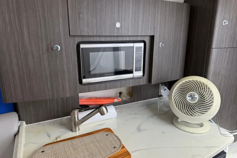 Slide: The Image of Compact kitchen area in a 2015 Intrepid 400 Cuddy boat with microwave and fan. - 25