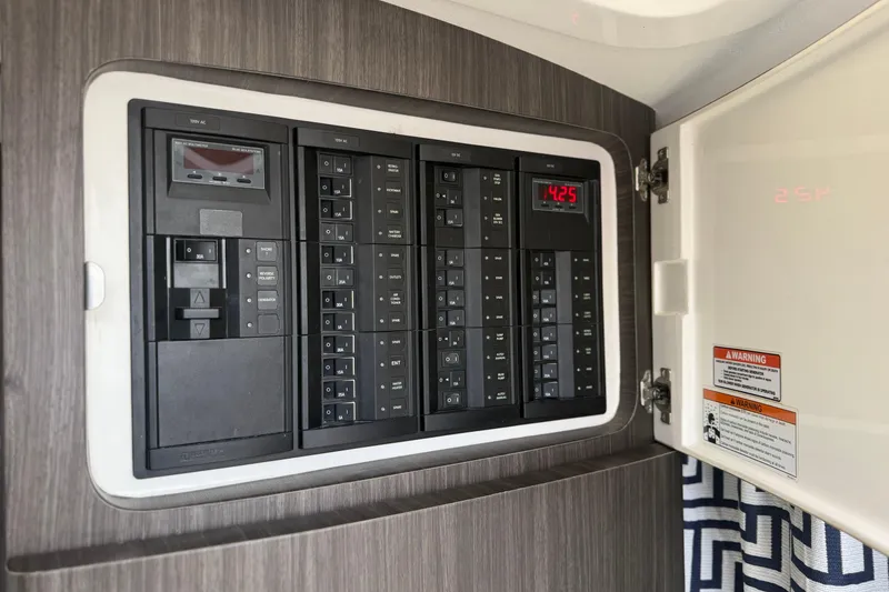 Slide: The Image of Electrical panel inside a 2015 Intrepid 400 Cuddy boat, featuring circuit breakers and digital display. - 27