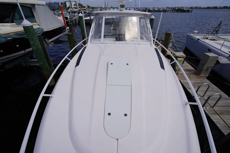 Slide: The Image of 2015 Intrepid 400 Cuddy boat docked at marina, showcasing sleek design and spacious deck. - 93
