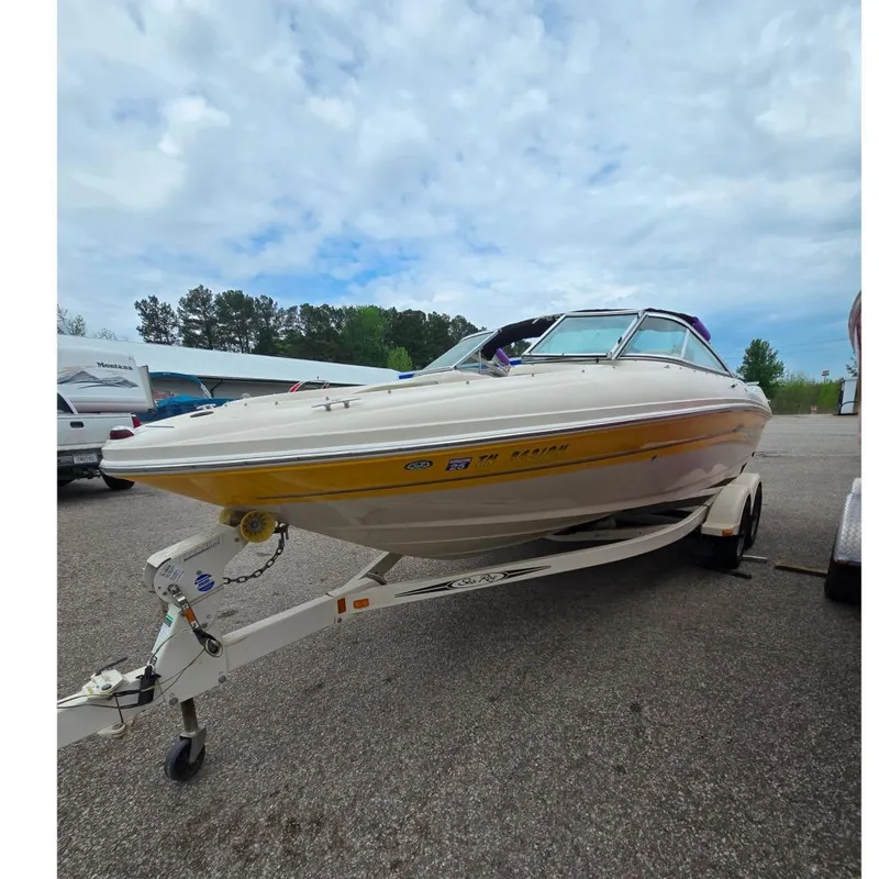 The Image of 2005 Sea Ray 200 Bow Rider boat on trailer, parked outdoors under cloudy sky. - 0