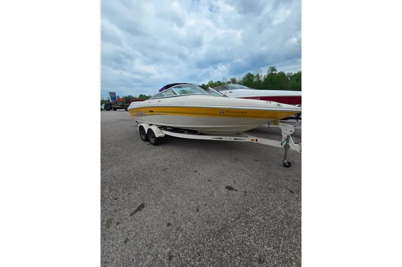 Slide: The Image of 2005 Sea Ray 200 Bow Rider boat on trailer, parked outdoors under cloudy sky. - 2