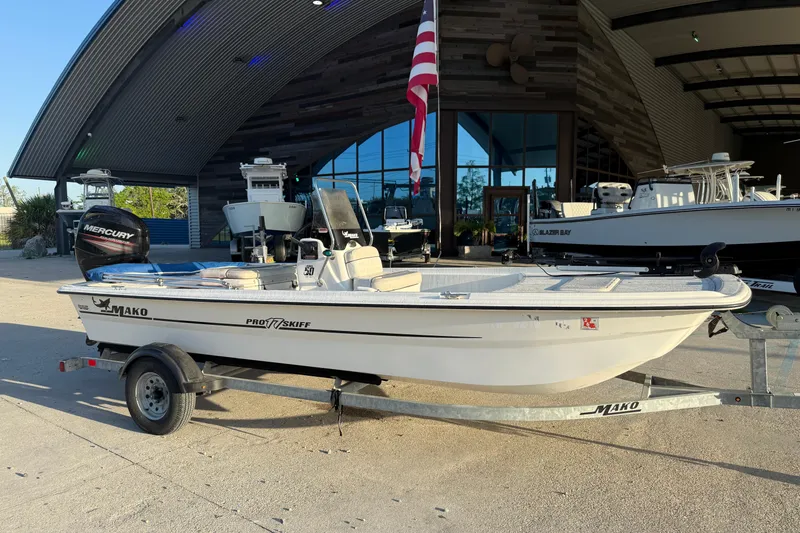 Slide: The Image of 2017 Mako Pro Skiff 17 CC boat on trailer outside a modern building. - 3