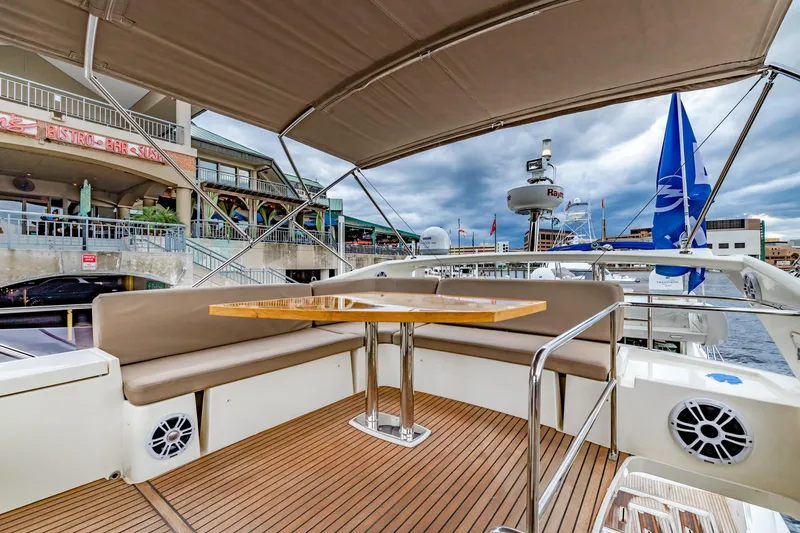 Slide: The Image of 2013 Prestige 500 Fly yacht deck with seating and table, docked near waterfront restaurants. - 34