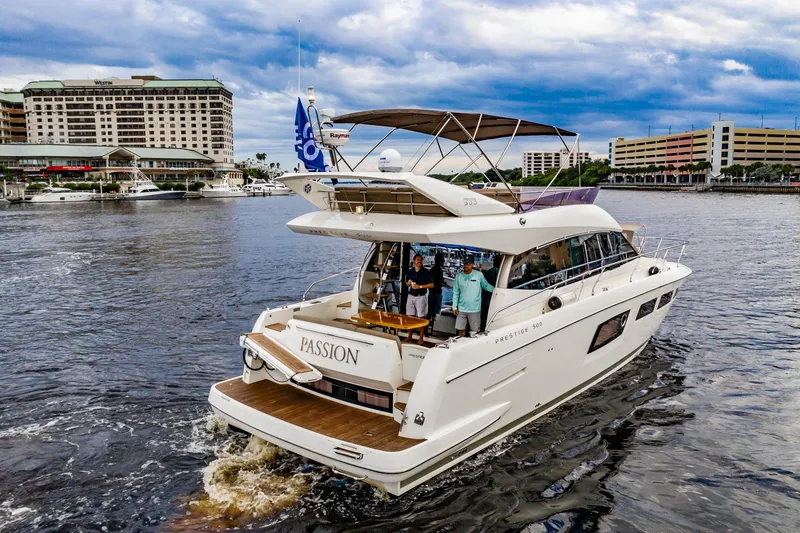 Slide: The Image of 2013 Prestige 500 Fly yacht named "Passion" cruising near waterfront buildings. - 6