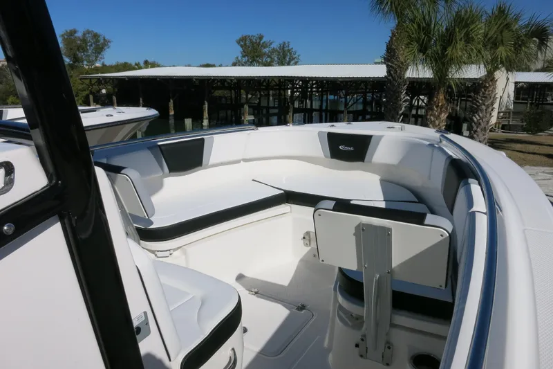 Slide: The Image of 2026 Robalo R230 Center Console boat interior with seating and table, docked near palm trees. - 14