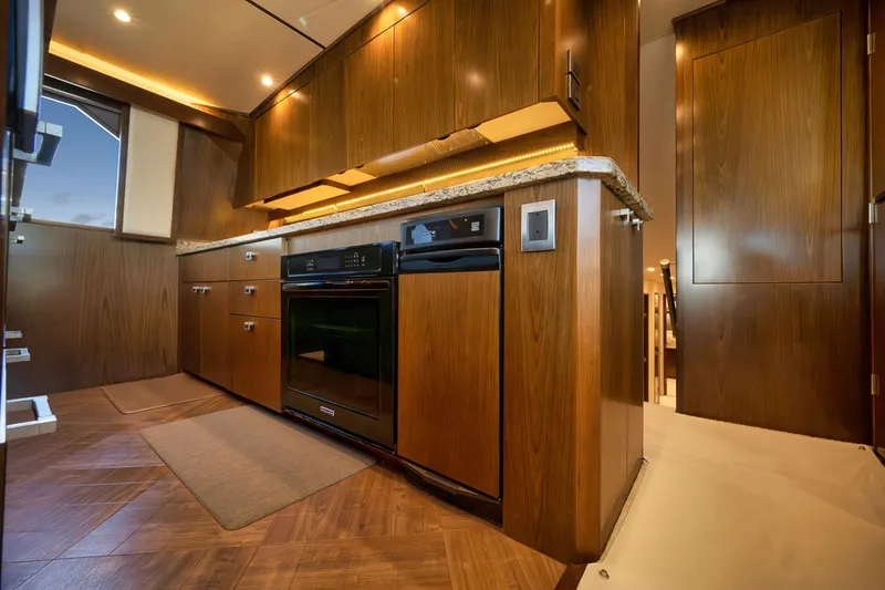 Slide: The Image of Luxurious kitchen interior of 2015 Viking 76 Enclosed Bridge yacht with wood cabinetry. - 31