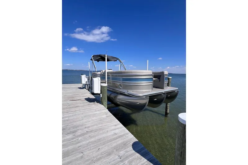 The Image of 2022 Harris Sunliner 230 pontoon boat docked on a sunny day. - 0