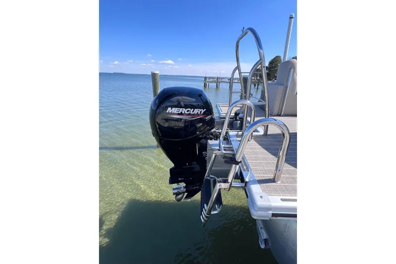 Slide: The Image of 2022 Harris Sunliner 230 pontoon boat with Mercury outboard motor on a sunny day. - 2