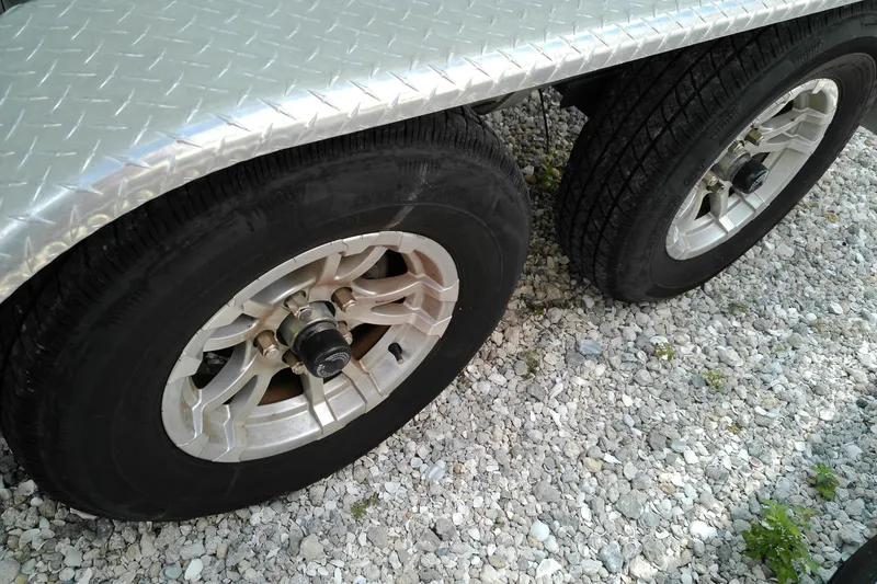 Slide: The Image of Trailer wheels on gravel, featuring a Glasstream 240 CC, 2023 model. - 2